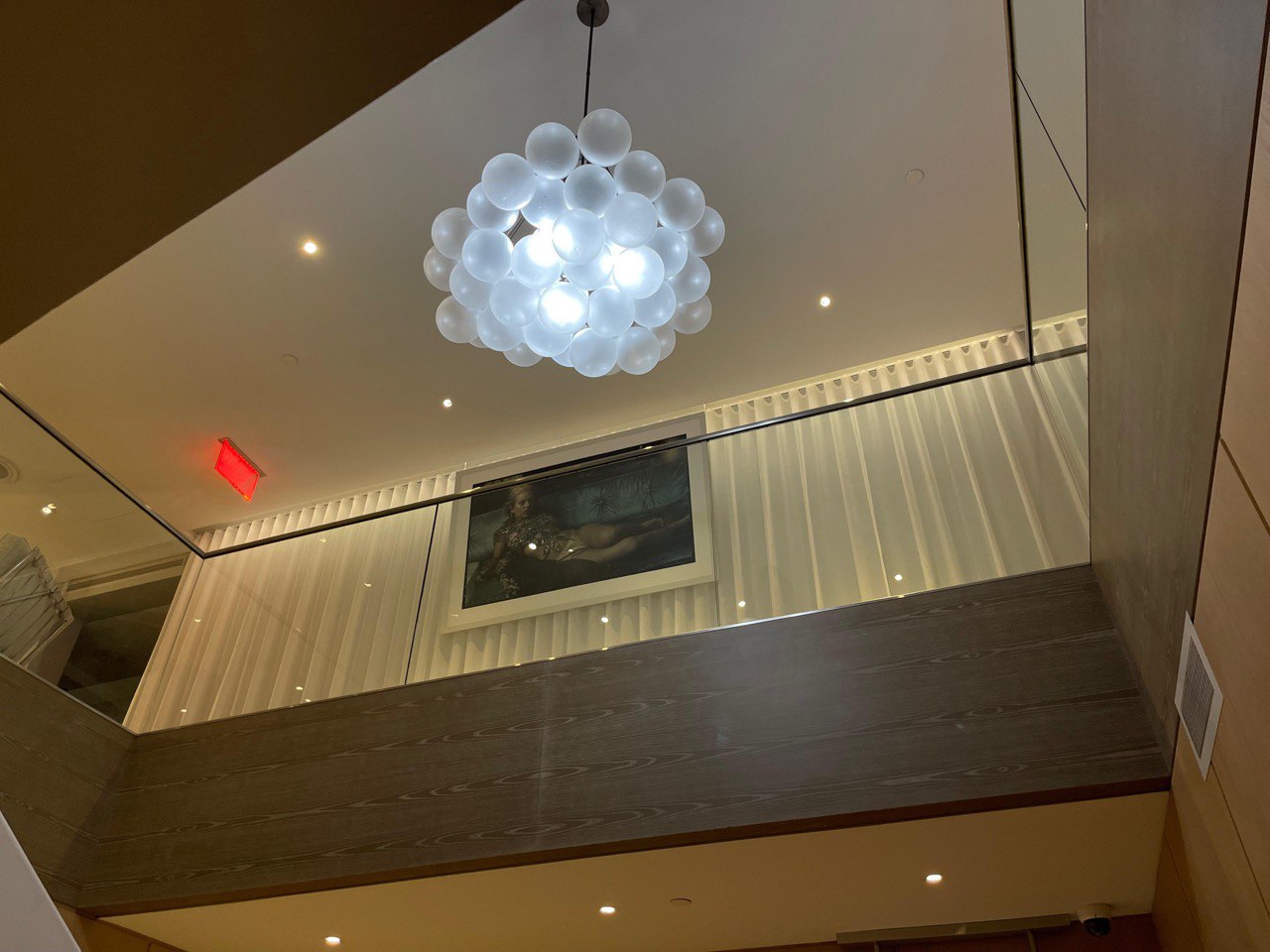 Modern glass-walled interior with a unique bubble chandelier and artwork.
