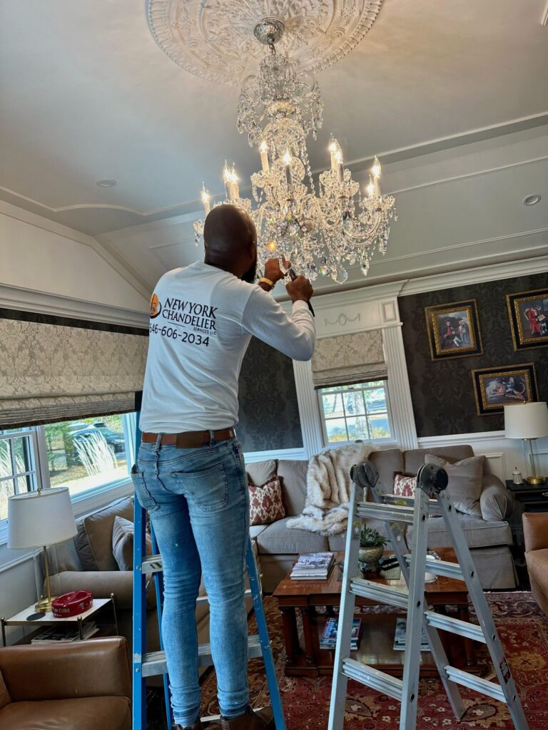 Technician installing chandelier in elegant living room