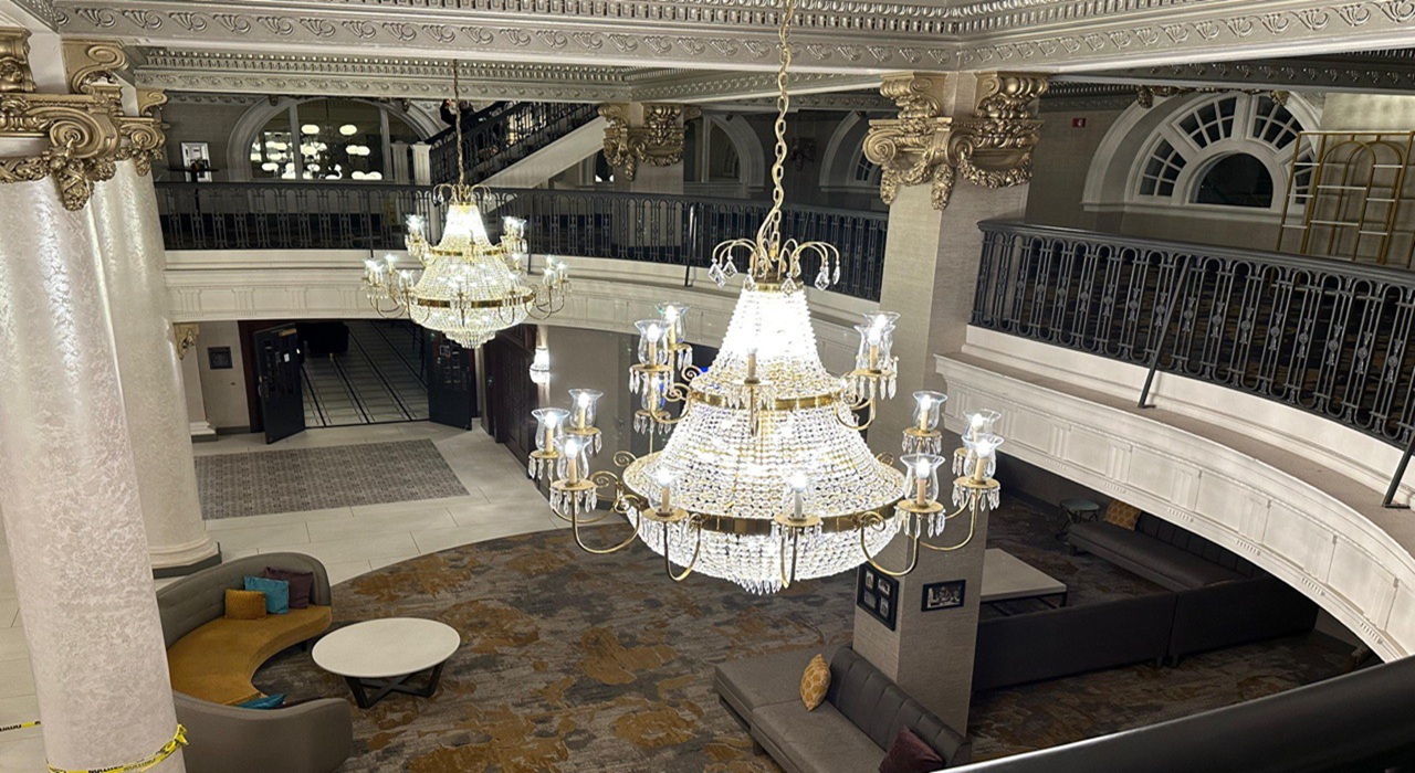 Grand hotel lobby with ornate chandeliers and plush seating.