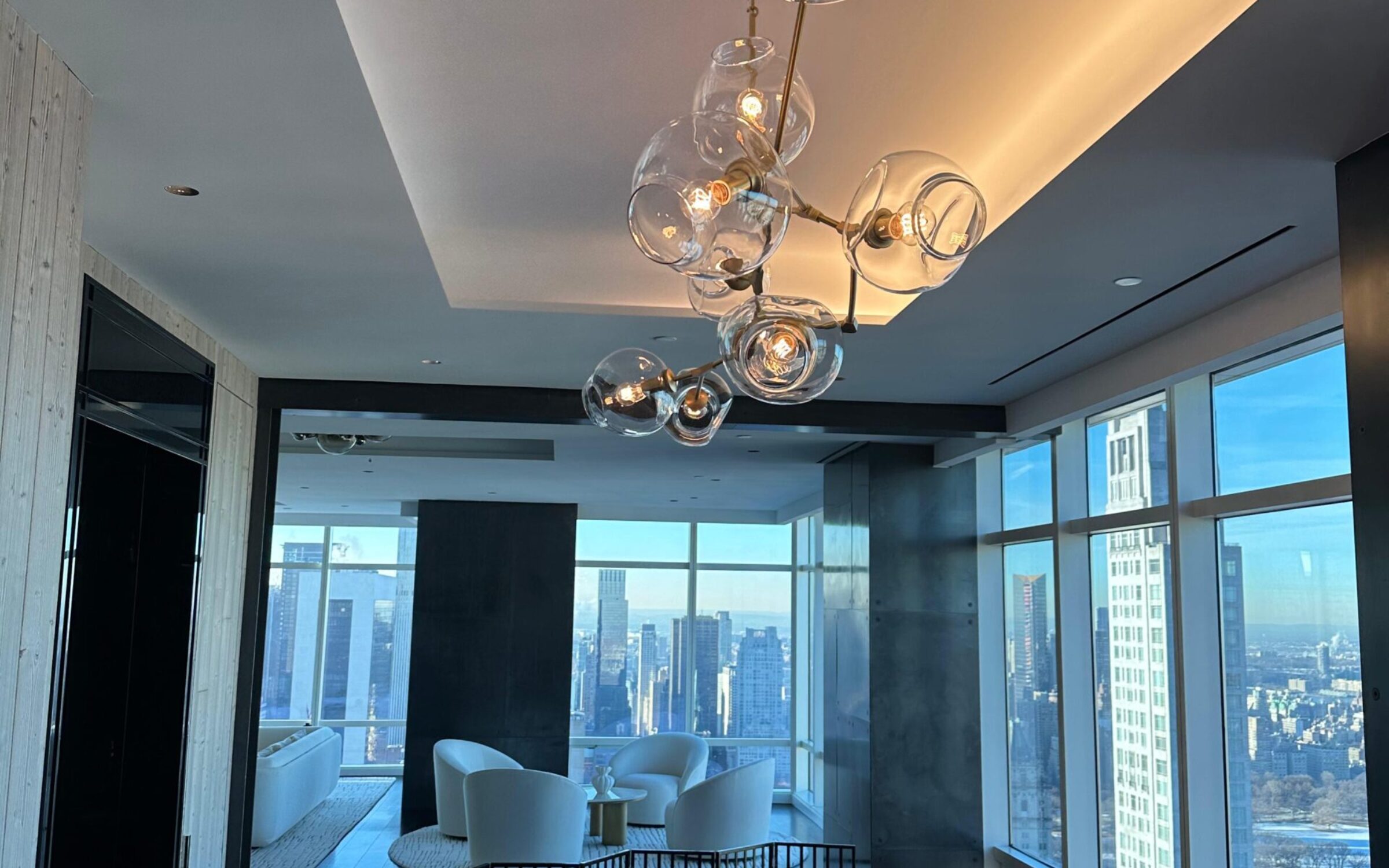 Modern dining room with city view, featuring a unique glass bubble chandelier.