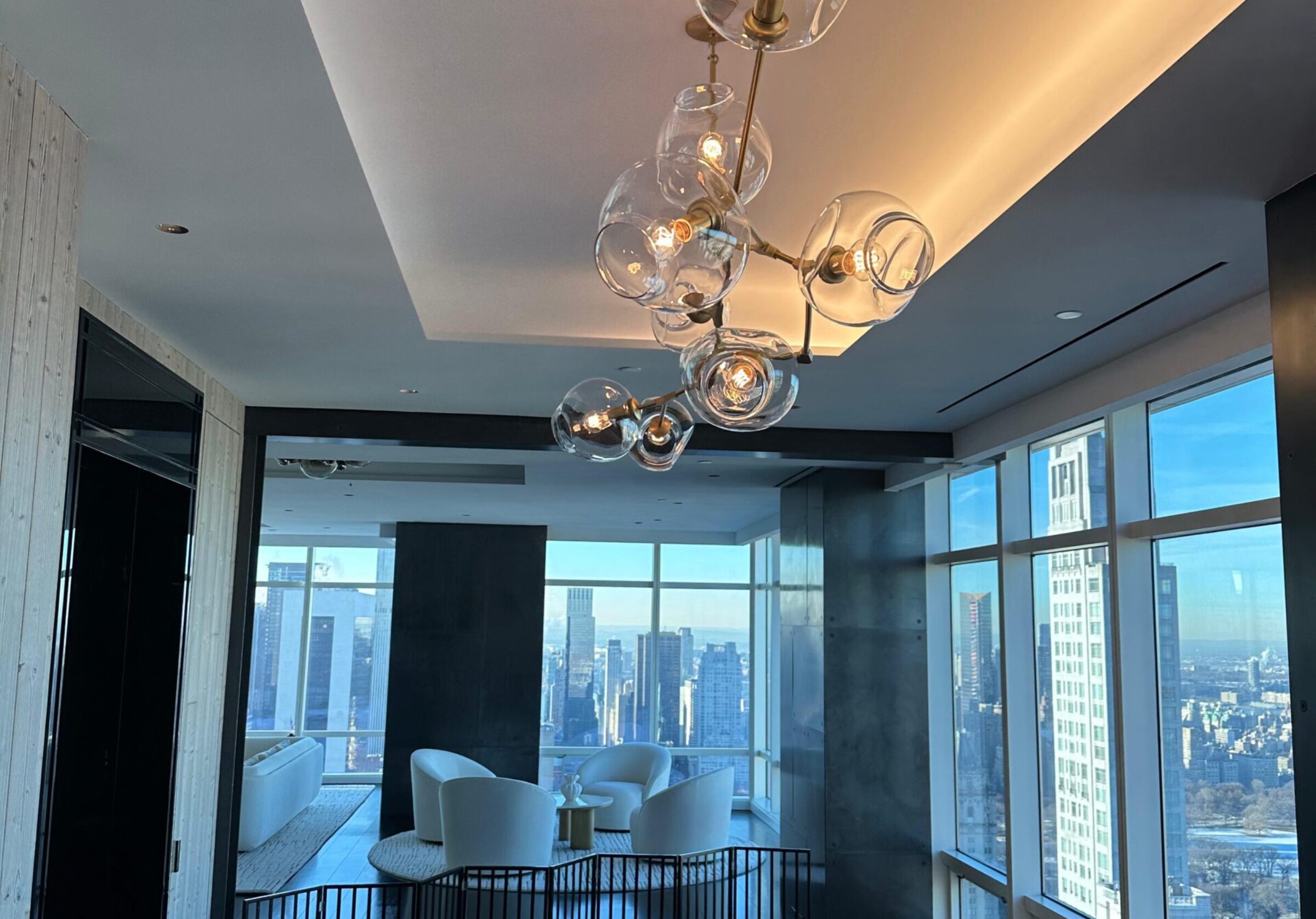 Modern dining room with city view, featuring a unique glass bubble chandelier.