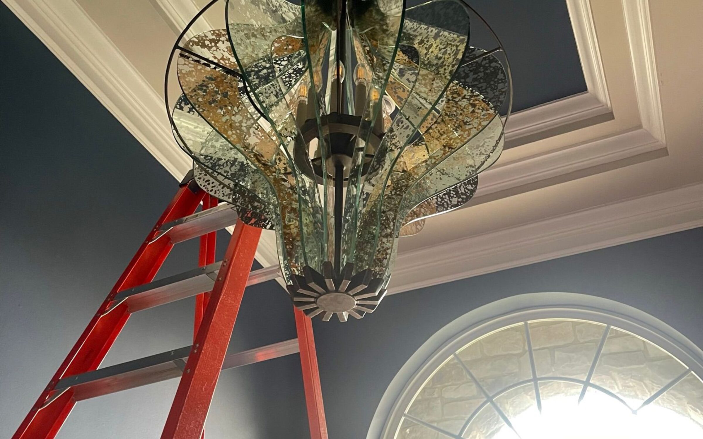 Elegant glass chandelier installation in progress, New York chandelier services.