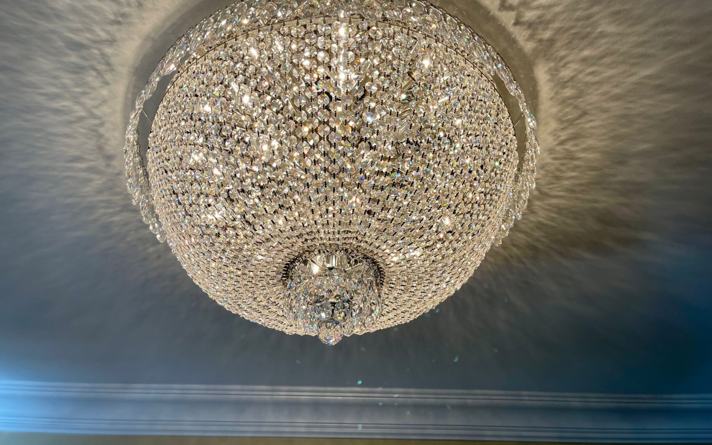 Elegant crystal chandelier casting reflections on ceiling