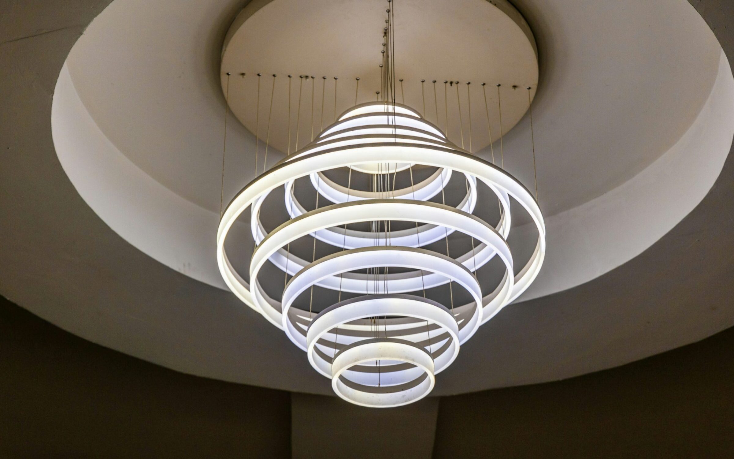 Modern LED chandelier with concentric rings, illuminating a circular ceiling recess.