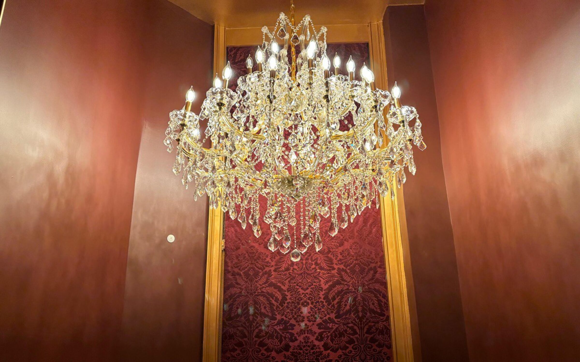 Elegant crystal chandelier in a luxurious burgundy hallway